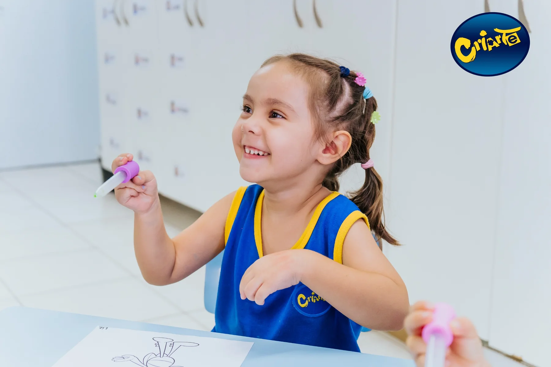 Aluna da Escola Criarte sorrindo durante uma atividade em sala